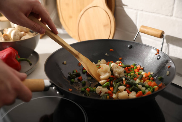 Man stirring mix of fresh vegetables in frying pan, closeup - Foto, Imagen