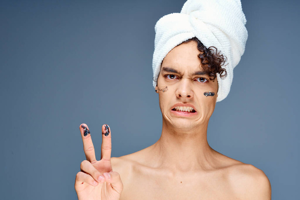 hombre con toalla de hombros desnuda en crema para la cabeza cosmetología de la piel limpia - Foto, imagen