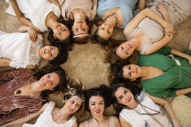 Top view group of happy female friends in bohemian hippie apparel lying circle together enjoying friendship having positive emotion. Smiling woman posing enjoying hen-party rejoicing have fun - Фото, зображення