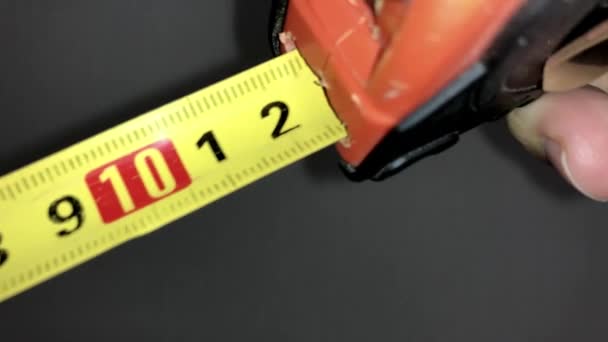 Woman stretching out yellow tape measure with numbers. close up. - Footage, Video