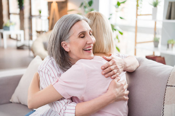 Photo of happy charming cheerful young woman and old lady hug love family indoors inside house home - Foto, Imagem