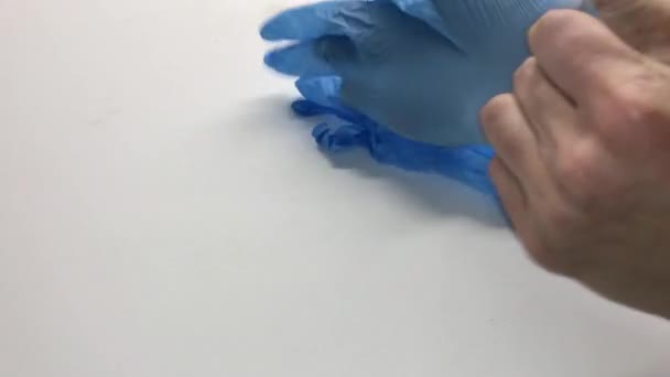 Dokter vrouwen doen blauwe latex handschoenen aan, close-up. Vrouwelijke handen. vrouwelijke handen in medische handschoenen kruisen hun vingers. - Video