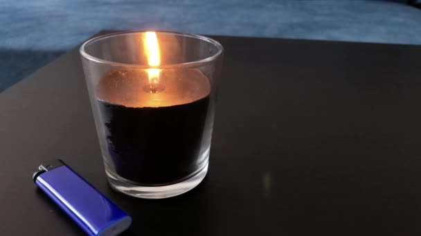 Blowing out a scented candle that is on the table and a lighter is lying nearby. - Footage, Video