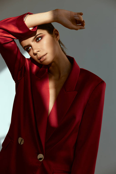 houkutteleva nainen, jolla on kirkas meikki näyttää sivuun punainen takki - Valokuva, kuva