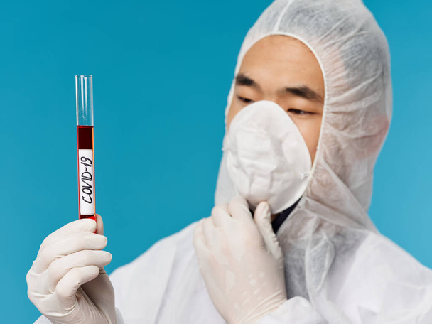 muž v ochranném lékařském oděvu krevní test diagnostika vyšetření modré pozadí close-up - Fotografie, Obrázek