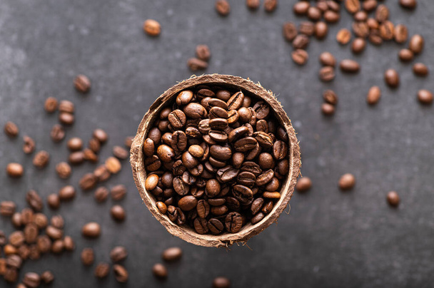 black coffee beans arabica, aromatic in a coconut dish, sprinkled beans on the table, close-up, top view - Foto, Bild