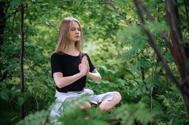 Practice of meditation and interaction with nature. Girl in green forest - Φωτογραφία, εικόνα