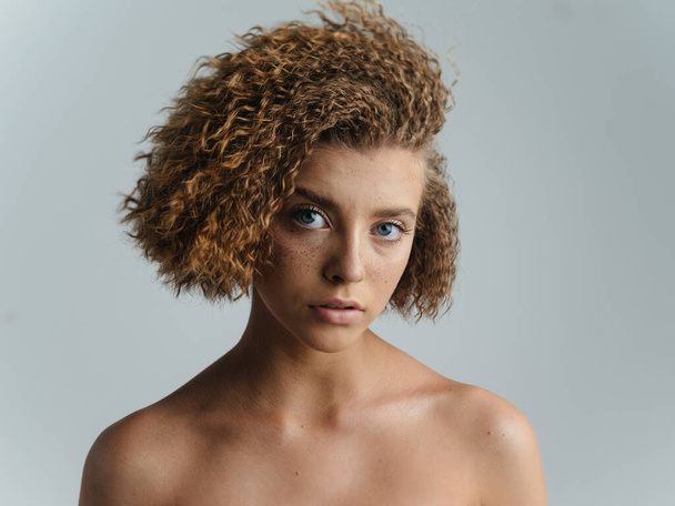 Beautiful woman portrait light background bared shoulders curly hair - Fotografie, Obrázek