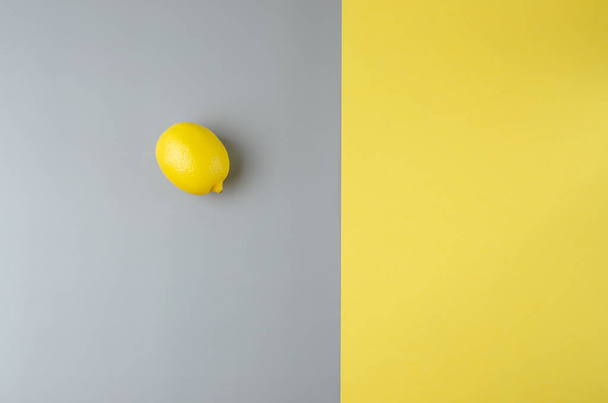 Lemon on a gray and yellow background. Trending color of year 2021 Illuminating and Ultimate gray. Top view minimal still life - Photo, Image