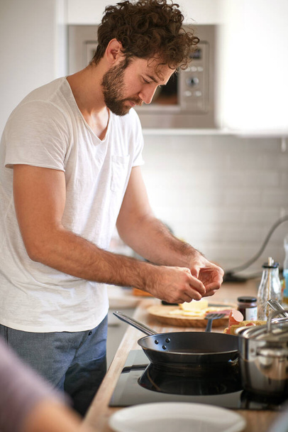 caucasian beardy guy with curly hair making breakfast. - Foto, Bild
