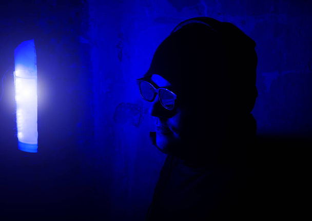 Studio d'enregistrement sonore. Jeune homme dans des lunettes et des écouteurs sur la soirée dans une boîte de nuit avec des néons. Amuse-toi bien. Loisirs vacances. - Photo, image