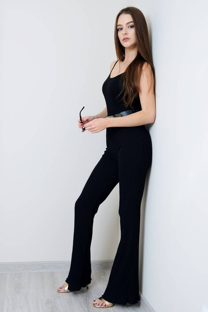 Young woman with black flared trousers and black top, woman staying at home. Polish model inside bright apartment.  - Photo, image