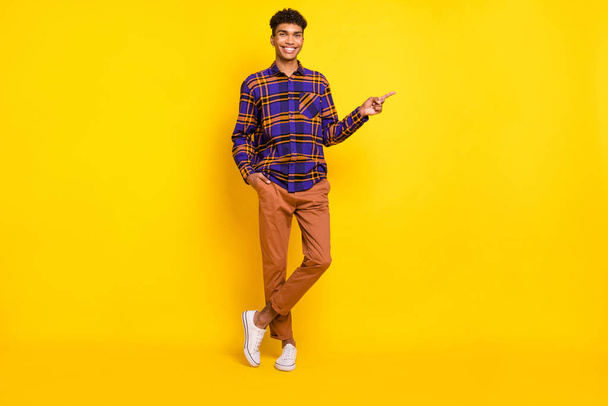 Full size photo of young man happy positive smile indicate finger empty space ad promo advise isolated over yellow color background - 写真・画像