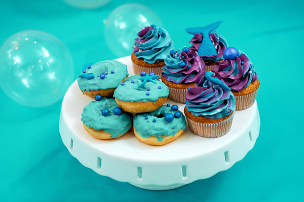 Kermamuffineja ja minidonitseja. Leivon lasten juhliin, joissa on meriteema. Jälkiruoat sinisessä - Valokuva, kuva