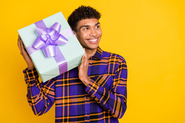 Photo portrait of curious guy try to guess what in the present gift box party looking empty space isolated vivid yellow color background - Fotografie, Obrázek