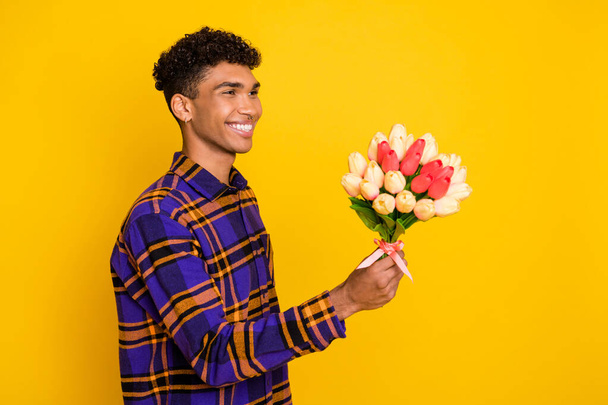 Side profile photo portrait of boyfriend giving flowers bouquet on date isolated on vibrant yellow color background - Zdjęcie, obraz