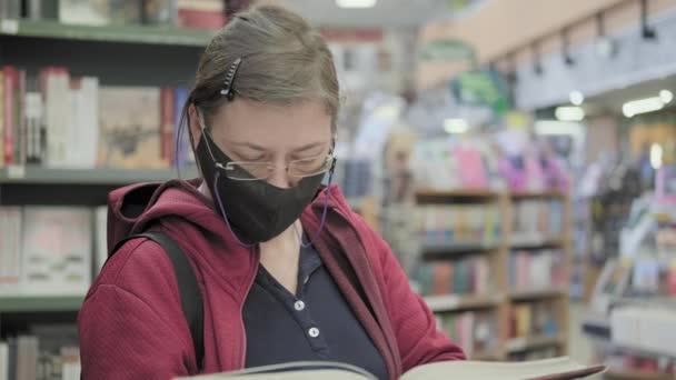  Femme masquée lit le livre. Elle plisse des yeux et enlève ses lunettes - Séquence, vidéo