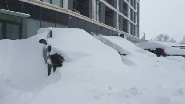 Autos, die nach einem Schneesturm von Schnee bedeckt sind. Wohnhaus im Hintergrund. - Filmmaterial, Video