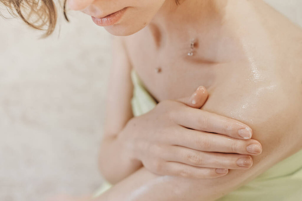 woman applying body butter on her shoulder. crop view. nourishing shea butter for smooth skin after bath. home spa and me time concept.  - Photo, Image