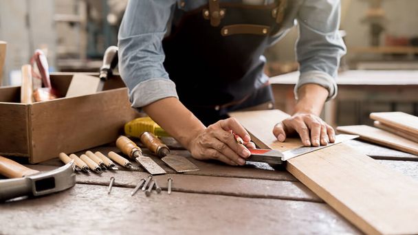 Ξυλουργός που εργάζεται με εξοπλισμό σε ξύλινο τραπέζι σε ξυλουργείο. Η γυναίκα δουλεύει σε ξυλουργείο.. - Φωτογραφία, εικόνα