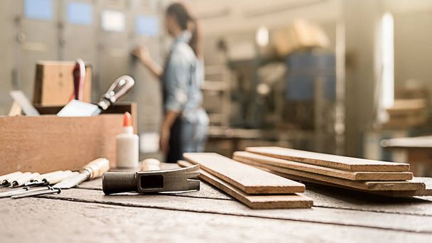 Ξυλουργός που εργάζεται με εξοπλισμό σε ξύλινο τραπέζι σε ξυλουργείο. Η γυναίκα δουλεύει σε ξυλουργείο.. - Φωτογραφία, εικόνα