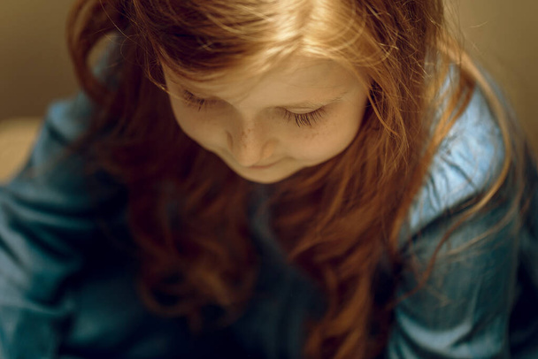hermosa niña con el pelo largo y rojo vestido azul de cerca, enfoque suave, espacio de copia - Foto, Imagen