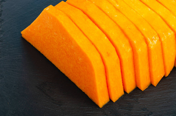 Нарезанные ломтики спелых оранжевых тыкв для приготовления пищи. Студия фото - Фото, изображение