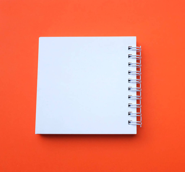plano y vista superior Bloc de notas en espiral blanco en blanco sobre un fondo naranja escritorio.Eucación y concepto de negocio - Foto, Imagen