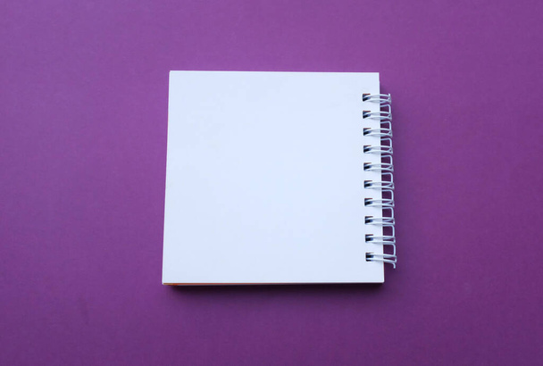 plano laico y vista superior Bloc de notas en espiral blanco en blanco sobre un fondo púrpura escritorio.Eucación y concepto de negocio - Foto, Imagen