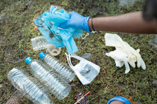 Schulterschuss eines Freiwilligen oder Fronthelfers, der während der Coronavirus-Covid-19-Pandemie medizinische und andere Plastikabfälle von der Straße sammelt. - Foto, Bild