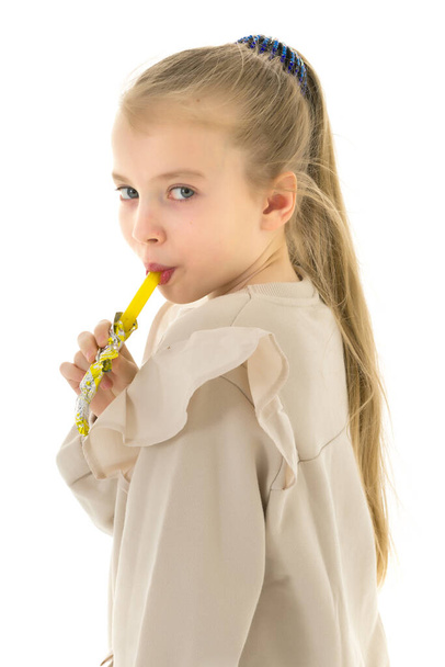 Cute little girl licks a candy. Concept of happy childhood - Φωτογραφία, εικόνα