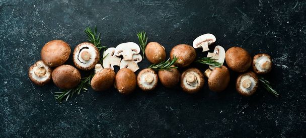 Fresh champignon mushrooms on a black stone background. Rustic style. Top view. - Photo, Image