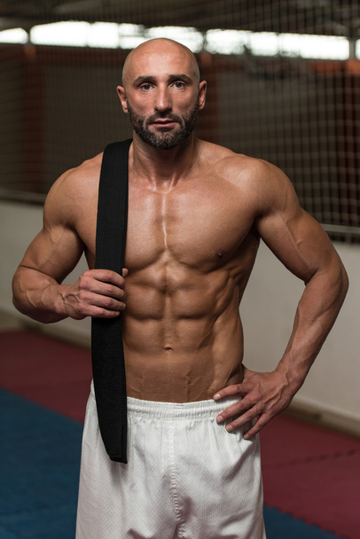 sexy muskulöser Mann mit schwarzem Gürtel auf der Schulter - Foto, Bild