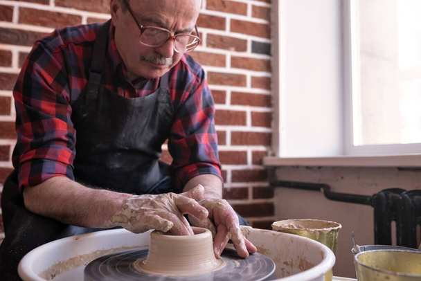 Senior male potter creating bowl in pottery workshop. - Photo, Image
