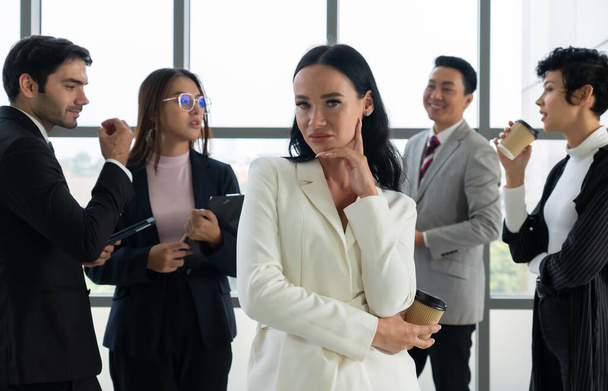 portrait of young caucasian confident businesswoman with smiling face stnading in office with background of multiethnic colleagues. diversity in business concept - Photo, Image