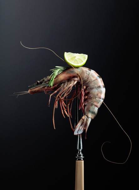 Fresh tiger prawn with rosemary and lime slice on a black background. Copy space. - Photo, Image