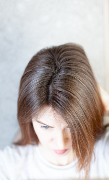 Der Kopf einer Frau mit grauen Haaren. Eine Frau frisiert sich die Haare. Braune Haare auf dem Kopf einer Frau in Großaufnahme. - Foto, Bild