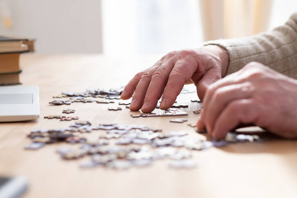 Senior male hands working on a puzzle at home - Fotoğraf, Görsel