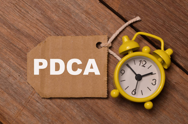 Vue du haut de l'horloge et note de service écrite avec PDCA signifie Plan Do Check Act ou Plan Do Check Ajuster - Photo, image