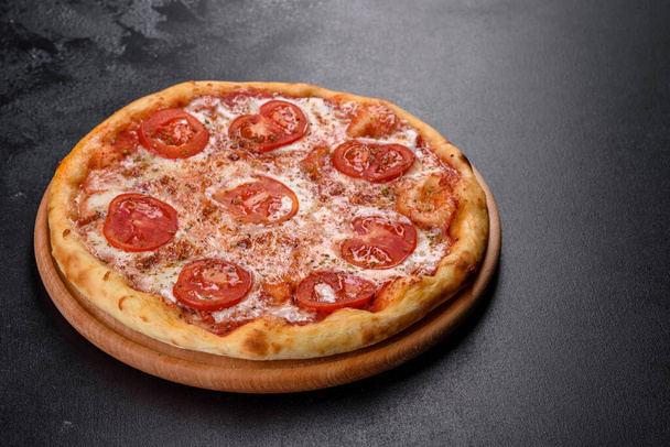 Leckere frische Ofenpizza mit Tomaten und Käse auf dunklem Betongrund - Foto, Bild