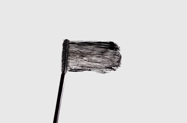 Un peine de pestañas y una mancha de rímel negro aislado sobre un fondo blanco. Maquillaje cosméticos Swatch - Foto, Imagen