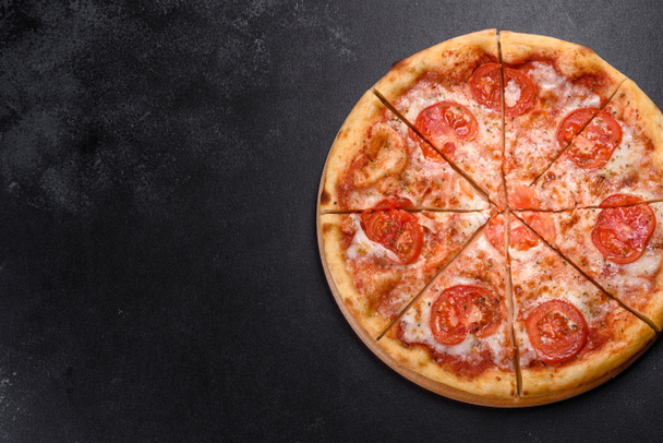 Ízletes friss sütő pizza paradicsommal és sajttal sötét beton alapon - Fotó, kép