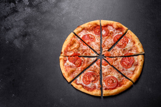 Ízletes friss sütő pizza paradicsommal és sajttal sötét beton alapon - Fotó, kép