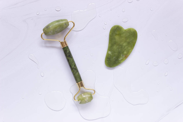 einen Guascha-Schaber und eine grüne Jade-Steinwalze. Selbstpflege, Anti-Aging-Gesichtsmassage, Wellness. - Foto, Bild