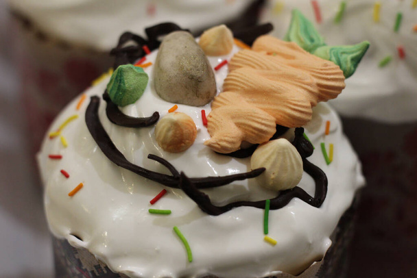 Gâteaux de Pâques fraîchement préparés en papier, décorés de fondant, glaçage au chocolat et oeufs et carottes de sucre - Photo, image