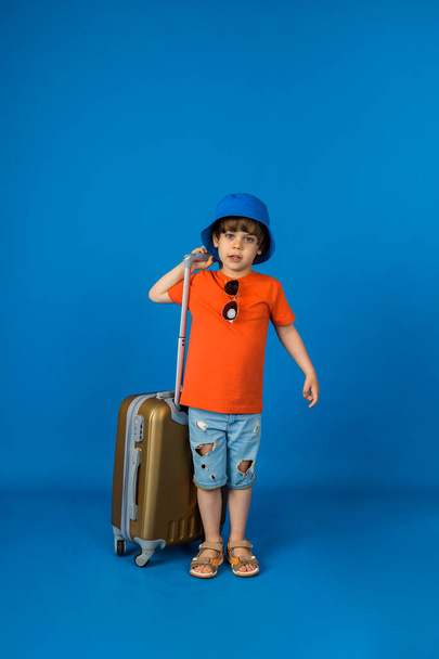 young traveler in panama stands with a suitcase on a blue background with space for text - Photo, Image