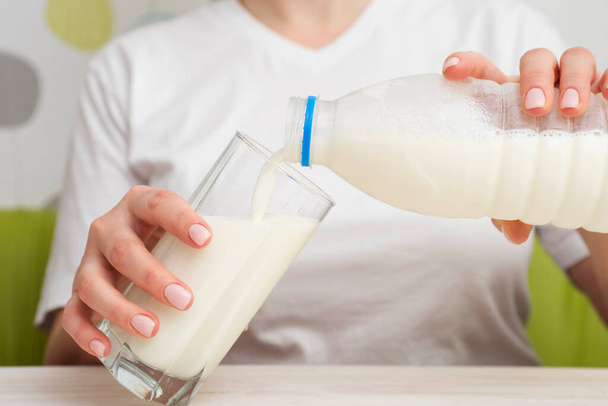 Una mujer está vertiendo leche de botella de plástico en un vaso. Dieta saludable. - Foto, imagen