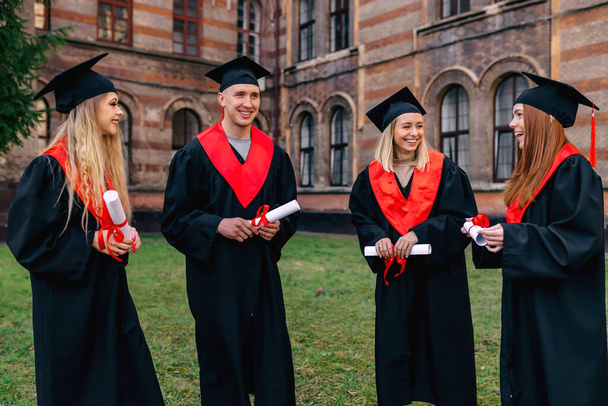 Vicces, öröm, a diákok fekete báli ruhákba vannak öltözve. osztálytársak séta az egyetem közelében, diploma után, bemutatása a diploma. - Fotó, kép