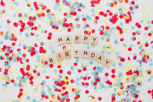 Happy birthday wooden sign on colorful confetti background - Фото, изображение