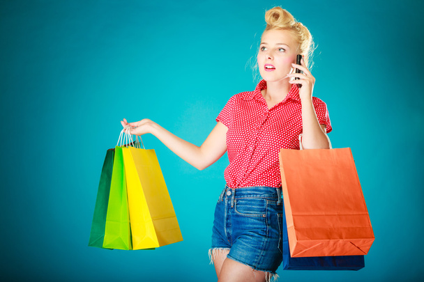Pinup girl with shopping bags calling on phone - Foto, imagen